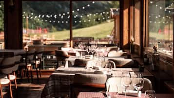 Un restaurant avec des nappes à carreaux, des meubles en bois et de grandes fenêtres donnant sur un paysage montagneux.