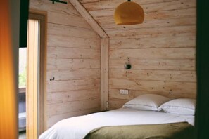 A wooden room with a bed, a door, and a hanging light fixture. - Les Cedres - Hotel, Restaurant & Spa (Saint-Sorlin-d'Arves)