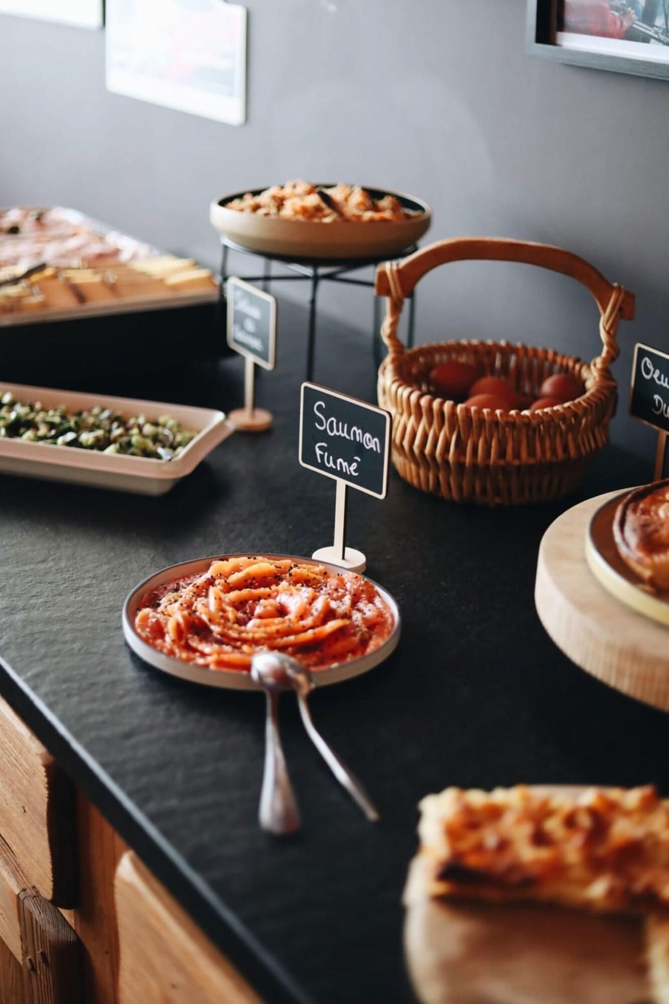 Une table de buffet proposant divers plats, notamment un plat de pâtes, un panier d’œufs et un panneau indiquant « Saumon fumé ».