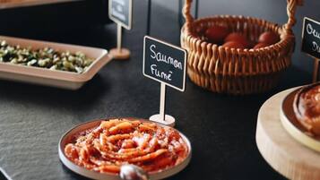 Een buffettafel met diverse gerechten, waaronder een bord pasta, een mand met eieren, en een bordje met de tekst 'Salmon Fume'.