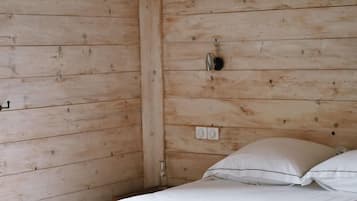 Una camera in legno con un letto, una lampada a sospensione e una presa elettrica.
