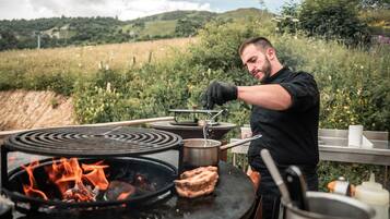 A person cooking outdoors with a portable stove and a grill.