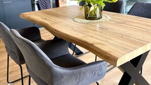 Zona pranzo moderna con tavolo in legno, sedie rivestite di grigio e un vaso di tulipani gialli.