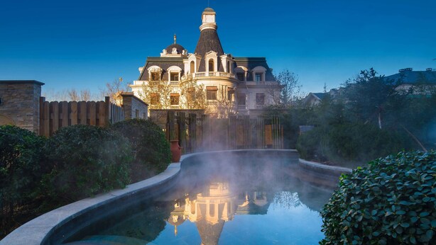 Un grand bâtiment imposant, richement décoré, avec une fontaine en premier plan.