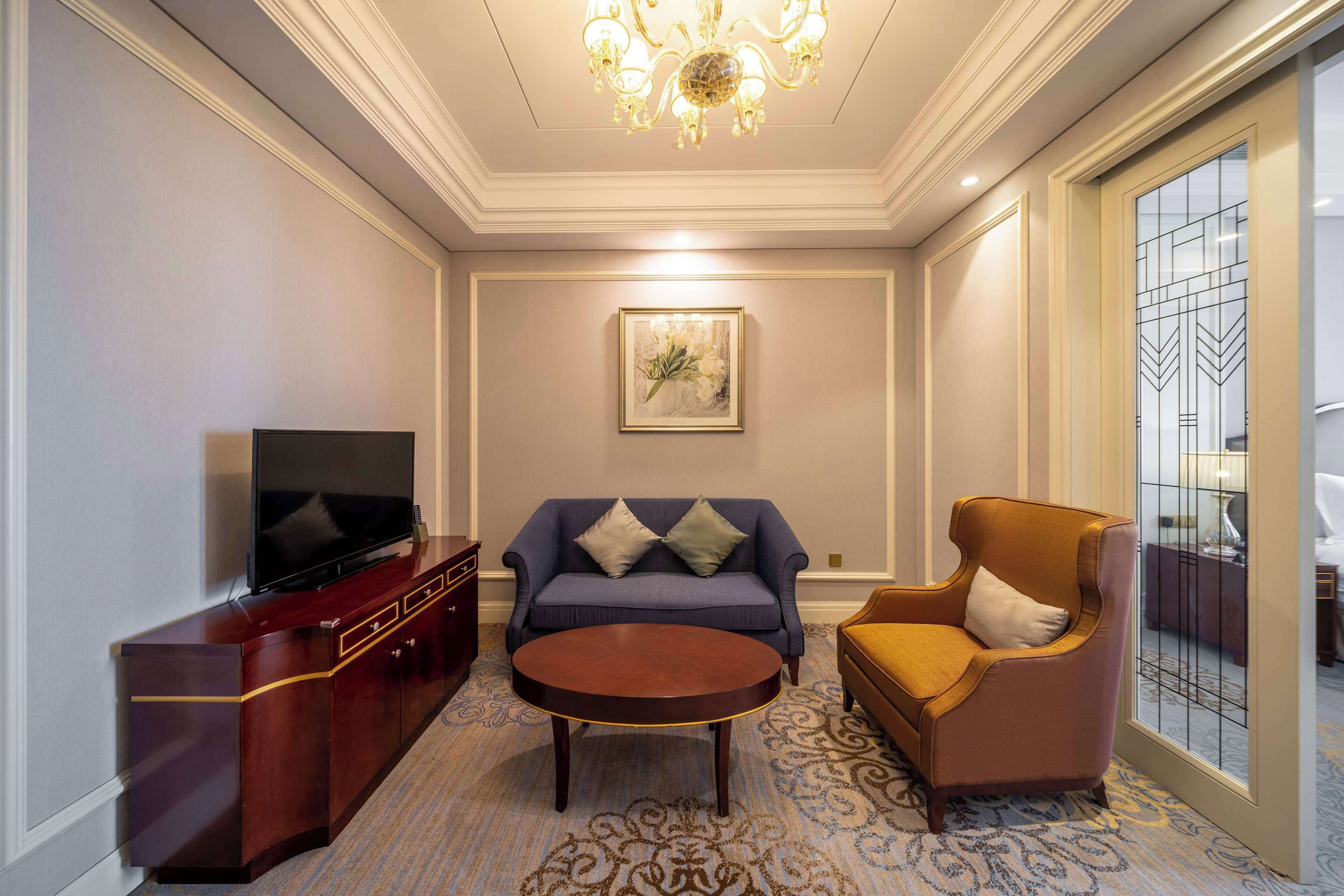 A living room with a flat-screen TV, a sofa, a coffee table, and a chair.
