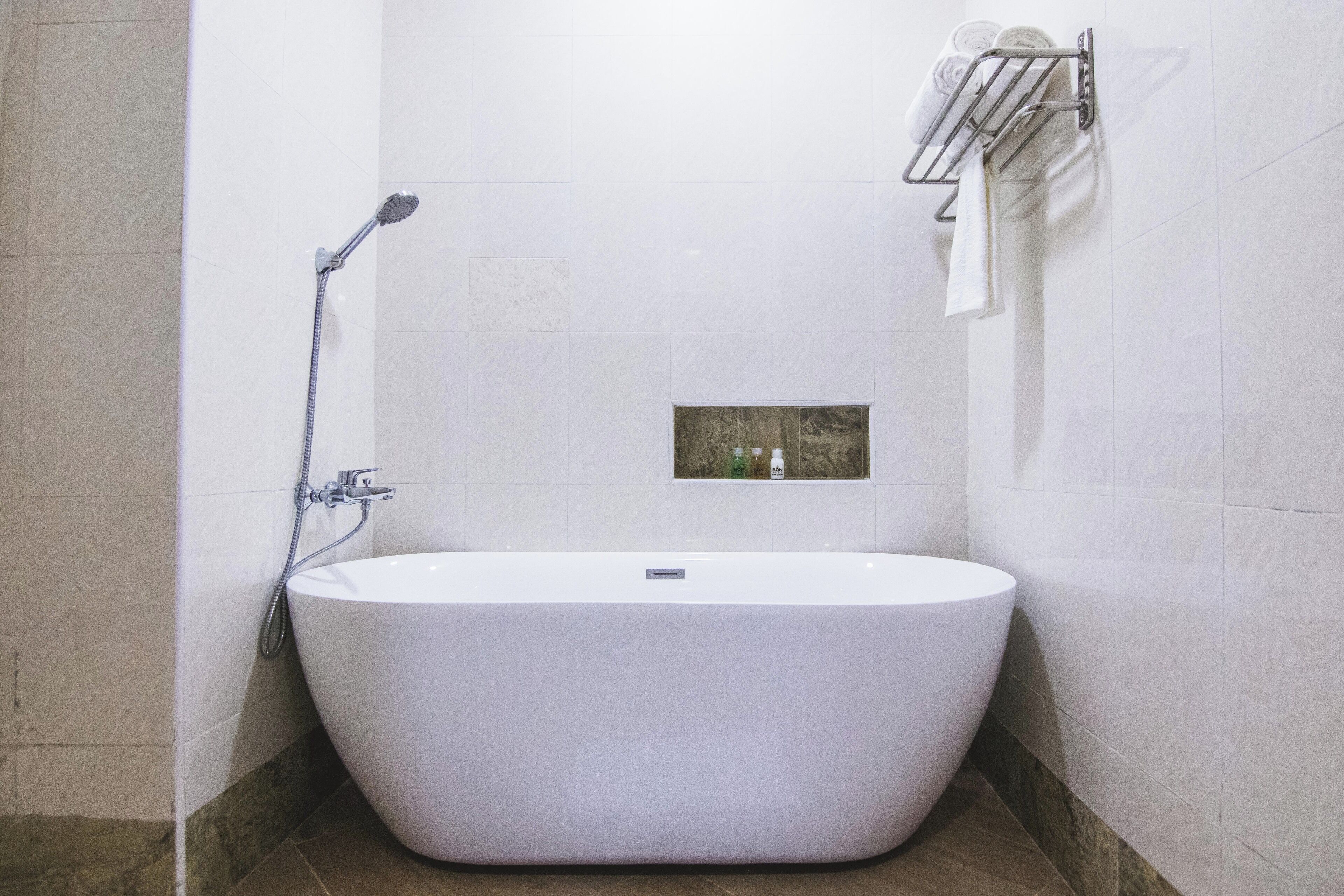 A modern bathroom with a freestanding bathtub, a showerhead, and a towel rack.