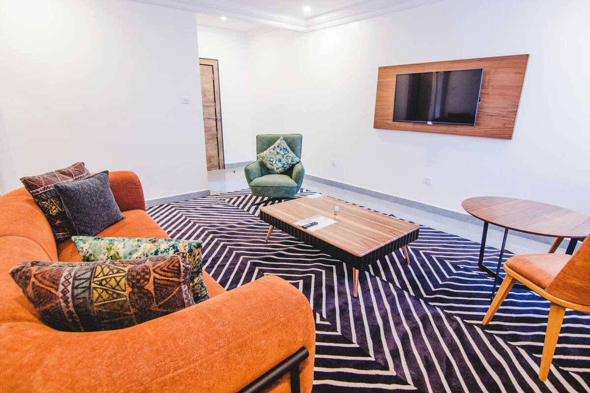 Una sala moderna con sofá, sillón, mesa de centro y una pequeña mesa con sillas.