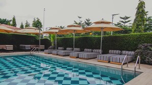 A pool with checkered tiles, lounge chairs, and umbrellas. - Bon Hotel Imperial (Abuja)