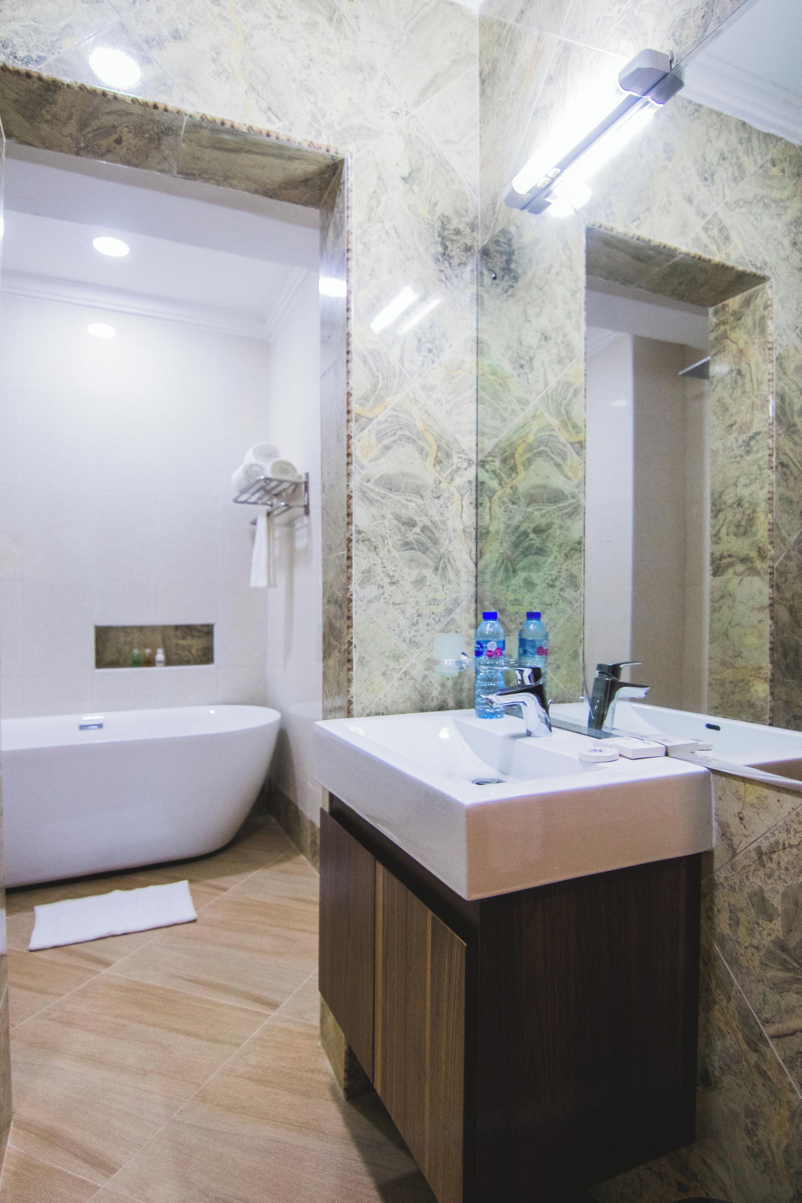 Un baño con una bañera independiente, un tocador con espejo y paredes de mármol.