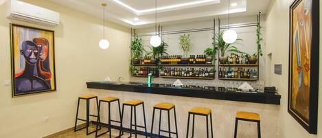 A bar area with a counter, stools, and shelves with bottles.