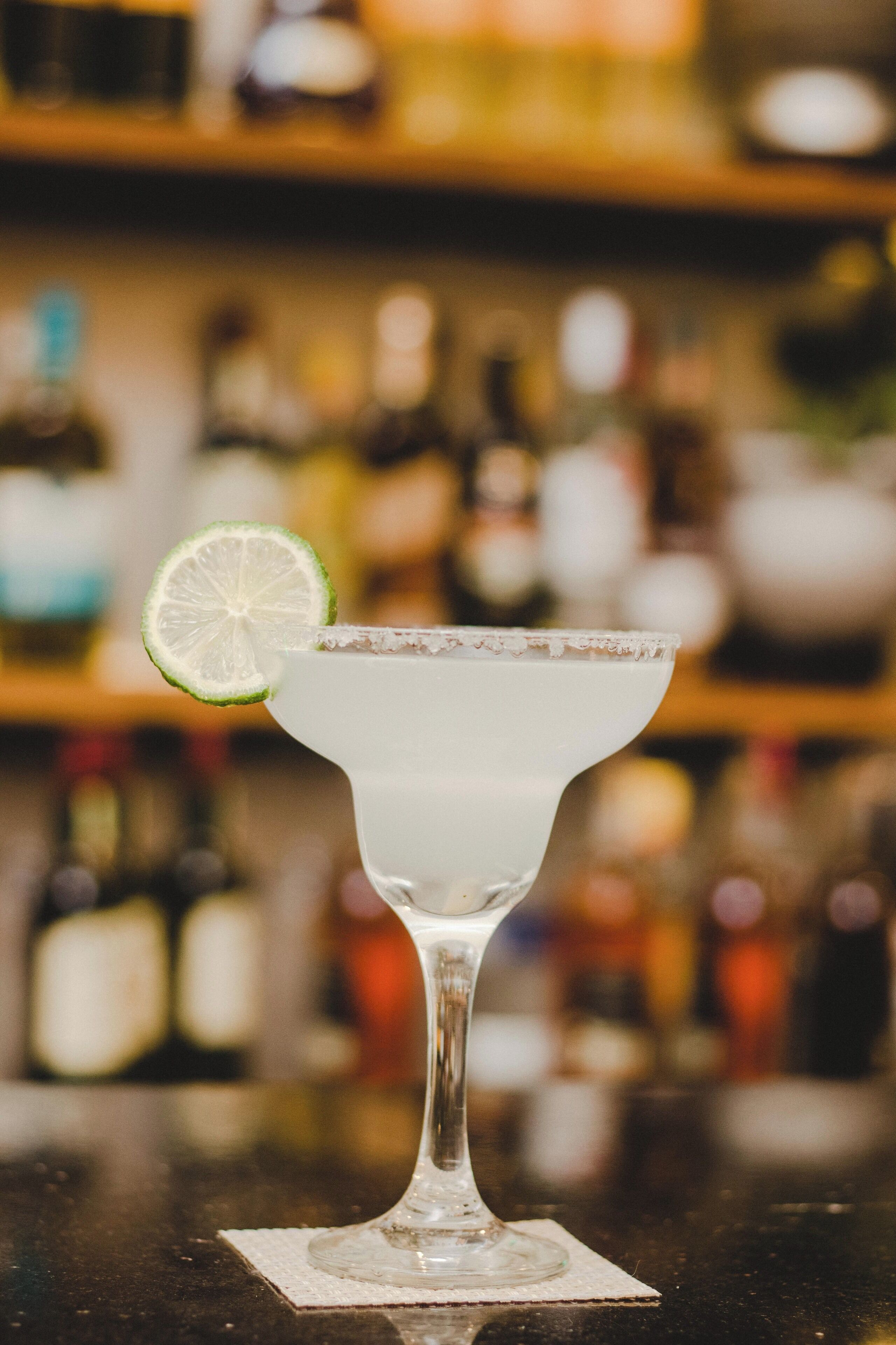 Un cóctel margarita con una rodaja de limón sobre la barra.
