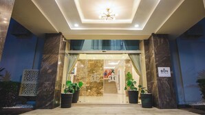 A hotel entrance with a modern design, featuring a glass door, marble pillars, and a ceiling light fixture. - Bon Hotel Imperial (Abuja)