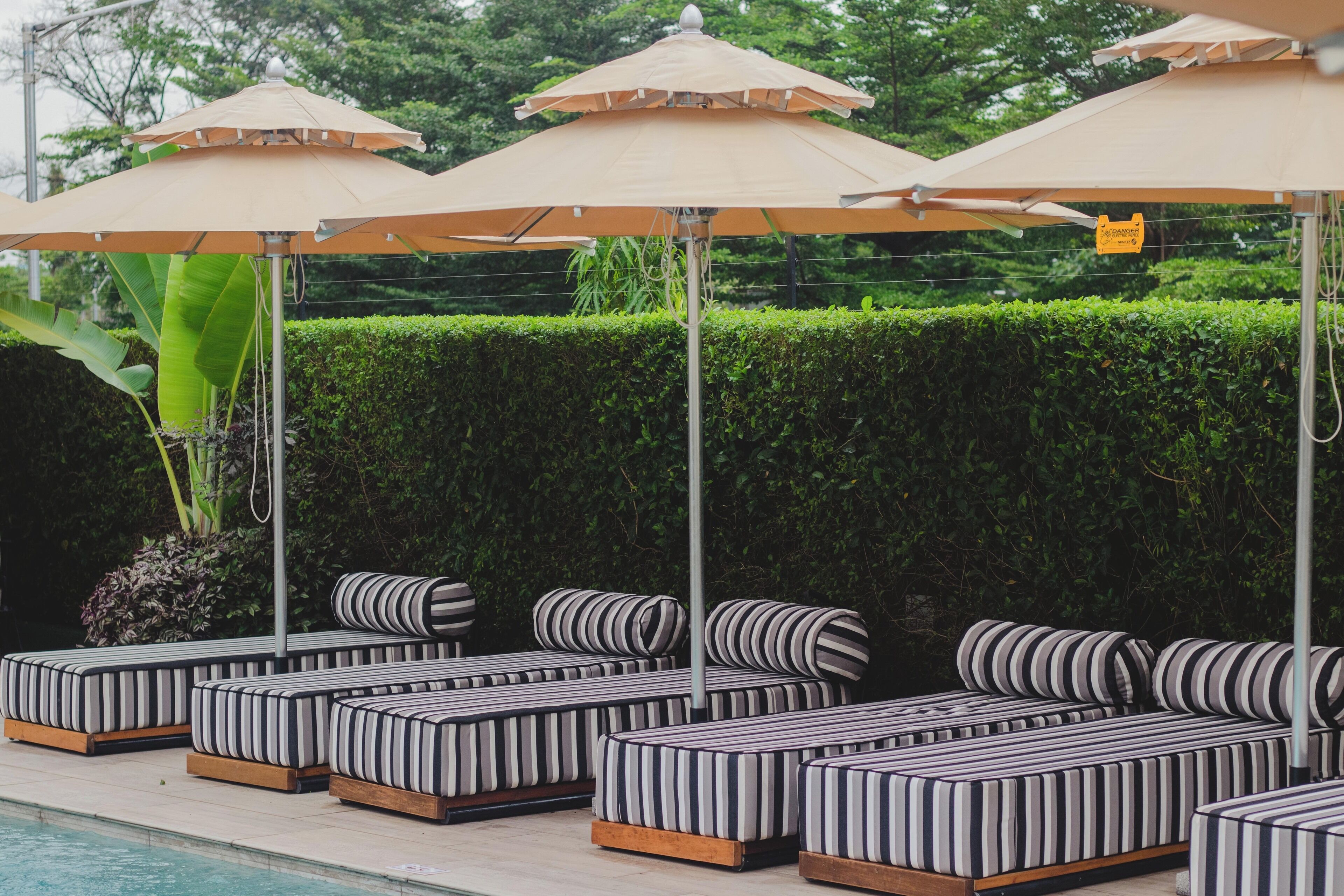 Outdoor seating with striped cushions and umbrellas by a pool.