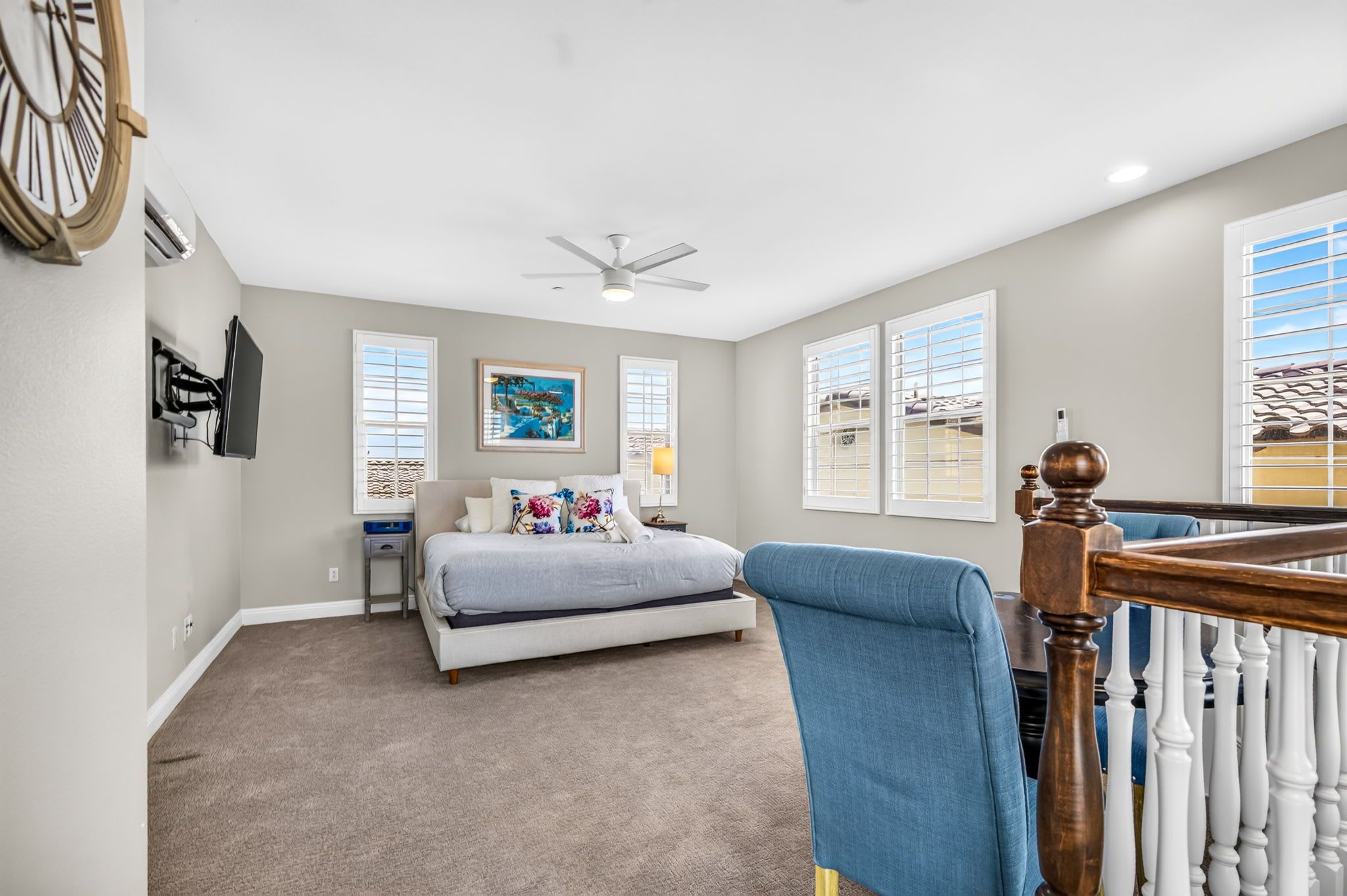A bedroom with a bed, a ceiling fan, a TV, and a window with blinds.