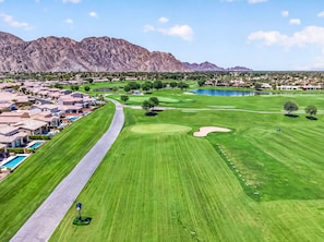 Un campo da golf con una strada, una piscina e edifici residenziali.