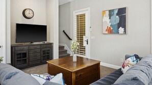 Ein Wohnzimmer mit Flachbildfernseher, Couch, Couchtisch und einem Gemälde an der Wand.