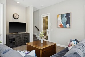 A living room with a flat-screen TV, a coffee table, a sofa, and a painting on the wall. - Exclusive Escape: Poolside Luxury near Scenic Golf (La Quinta)