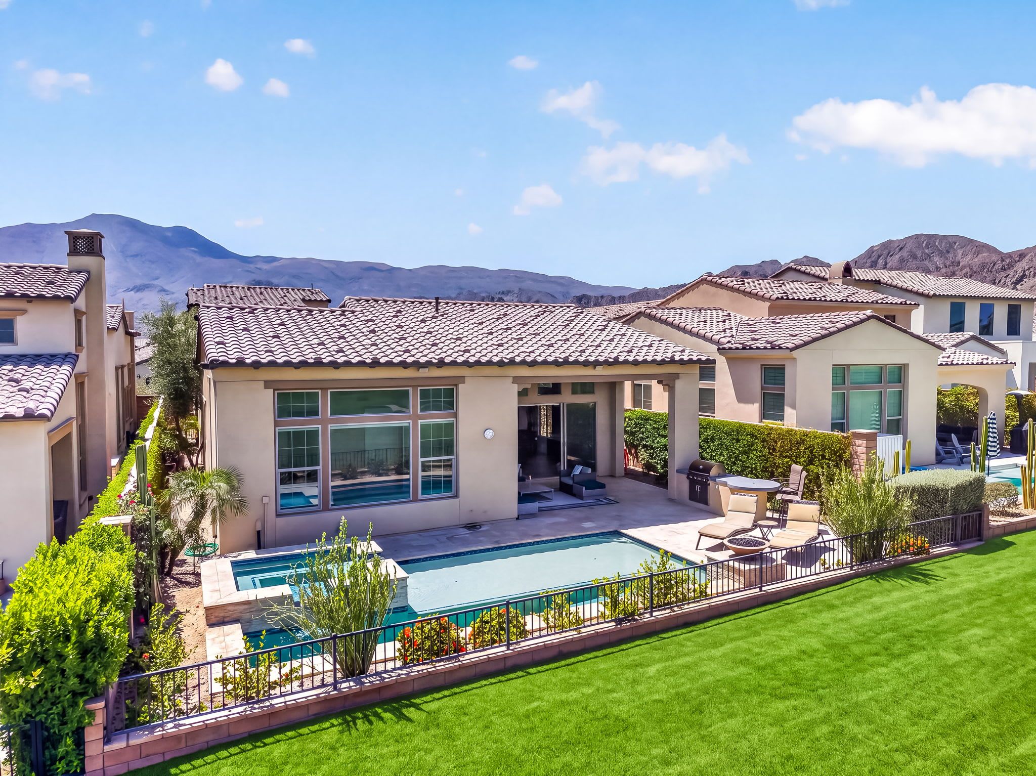 Una propiedad residencial con piscina, muebles de patio y vistas a montañas.