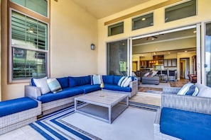 A spacious living area with a sectional sofa, a coffee table, and a view of the kitchen and dining area through glass doors.