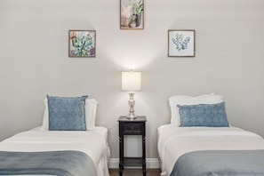A hotel room with two beds, a nightstand with a lamp, and three framed floral artworks on the wall. - Exclusive Escape: Poolside Luxury near Scenic Golf (La Quinta)