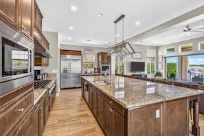 A modern kitchen with a large island, stainless steel appliances, and a view to the outdoors.