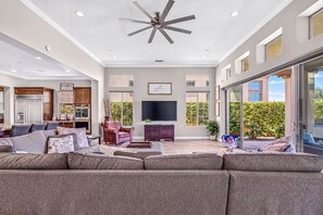 A spacious living room with a large sectional sofa, a fireplace, and a flat-screen TV. - Exclusive Escape: Poolside Luxury near Scenic Golf (La Quinta)