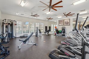 A gym with ceiling fans, treadmills, weight machines, and exercise balls.