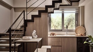 A modern kitchen with wooden cabinets, a built-in stove, and a window with a view of trees. - Liostasi Village  (Zakynthos)