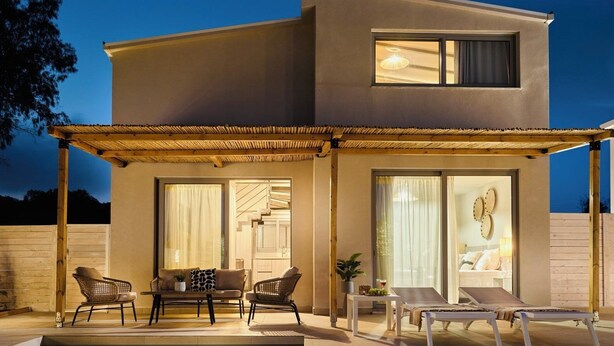 A modern two-story house with a covered patio area, furnished with a sofa, chairs, and a table. - Liostasi Village  (Zakynthos)