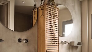 A bathroom with two large white sinks, a wooden cabinet with a plant, and a round mirror. - Liostasi Village  (Zakynthos)