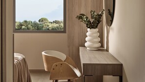 A modern room with a large window, a wooden desk, a white vase with greenery, and a curved chair. - Liostasi Village  (Zakynthos)