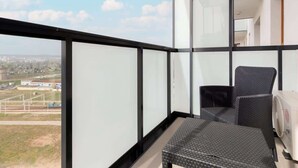 A balcony with a view of a cityscape, a wicker chair, and a white radiator.