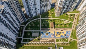 A high-rise residential building with multiple balconies, a central courtyard with greenery, and a playground area.