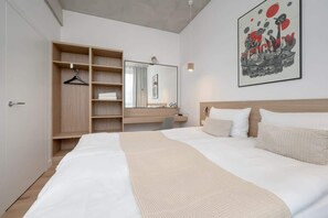 A hotel room with a large bed, a wooden wardrobe, a desk, a chair, and a large mirror.