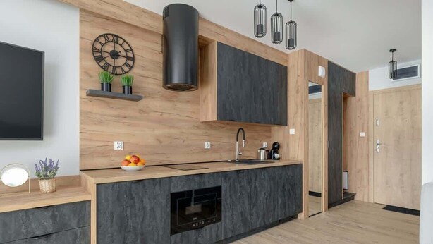 Een moderne keuken met een ingebouwde oven, een spoelbak en een houten aanrecht.