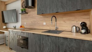 Een moderne keuken met een ingebouwde oven, een RVS spoelbak en een koffiezetapparaat.
