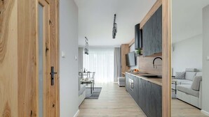 Een moderne keuken met een centraal eiland, houten vloeren en een eethoek met een tafel en stoelen.