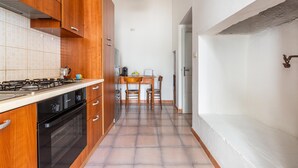 A kitchen with wooden cabinets, a stove, and a dining area with a table and chairs. - 3836 Da Donatuccia by Barbarhouse (Presicce-Acquarica)