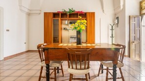 A dining area with a wooden table, chairs, and a vase of yellow flowers. - 3836 Da Donatuccia by Barbarhouse (Presicce-Acquarica)
