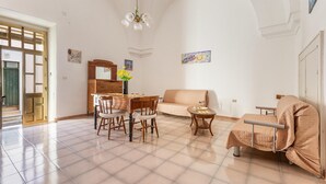 A spacious living room with a dining area, a sofa, and a covered chair. - 3836 Da Donatuccia by Barbarhouse (Presicce-Acquarica)