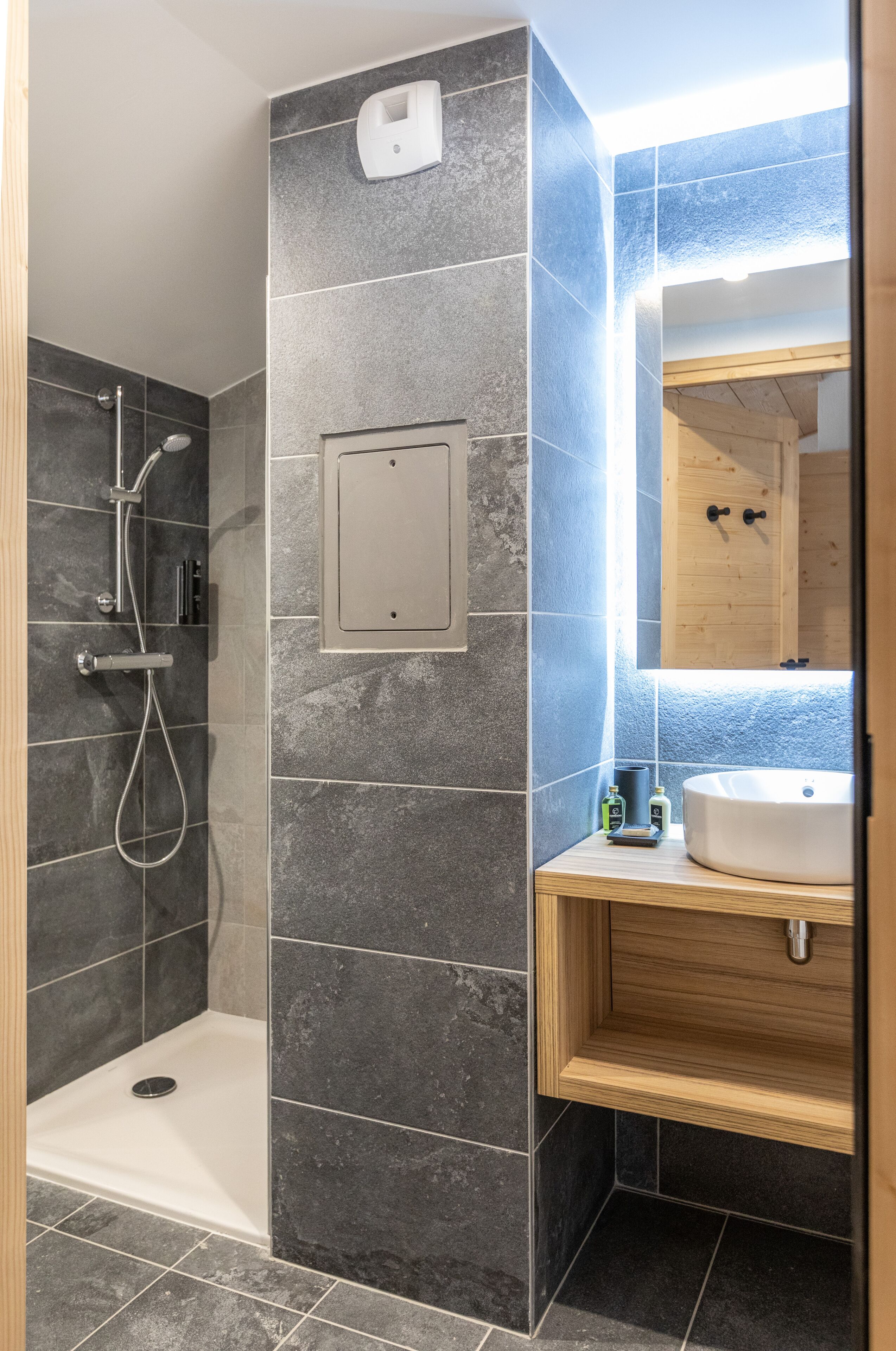 Un baño moderno con ducha, lavabo y espejo.