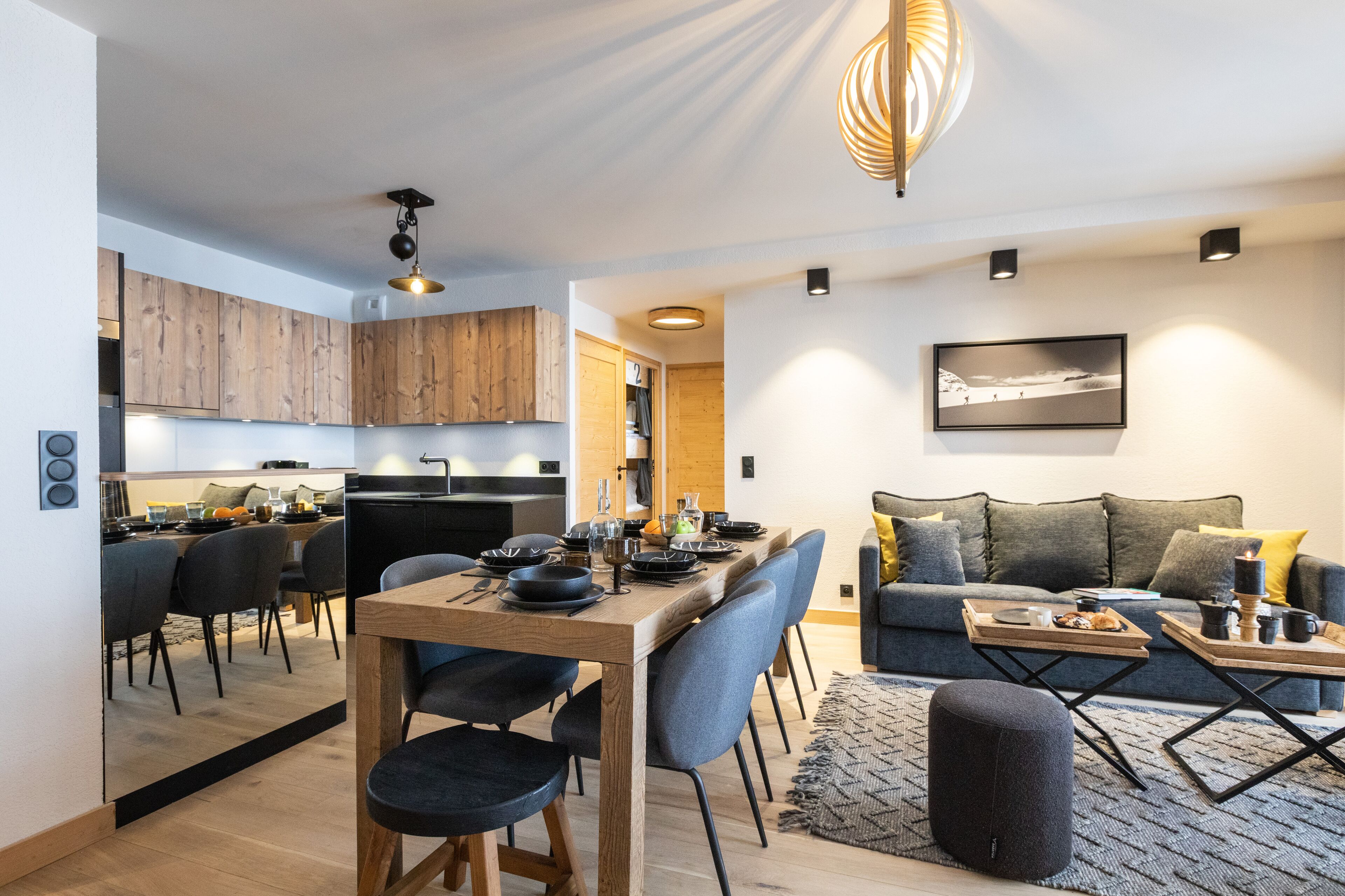 Una cocina moderna con armarios de madera, un comedor con mesa y sillas de madera, y una sala de estar con sofá y mesa de centro.
