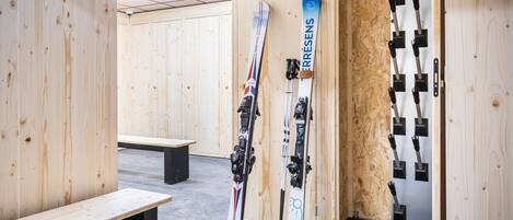 Ein Holzraum mit Bänken und an den Wänden abgestellten Skiern.