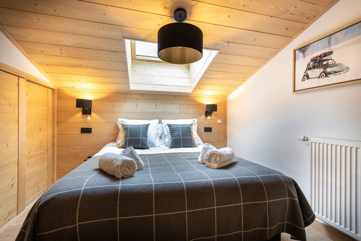 Ein gemütliches Zimmer mit einem Bett, zwei Wandlampen, einem Dachfenster und einer Heizung.