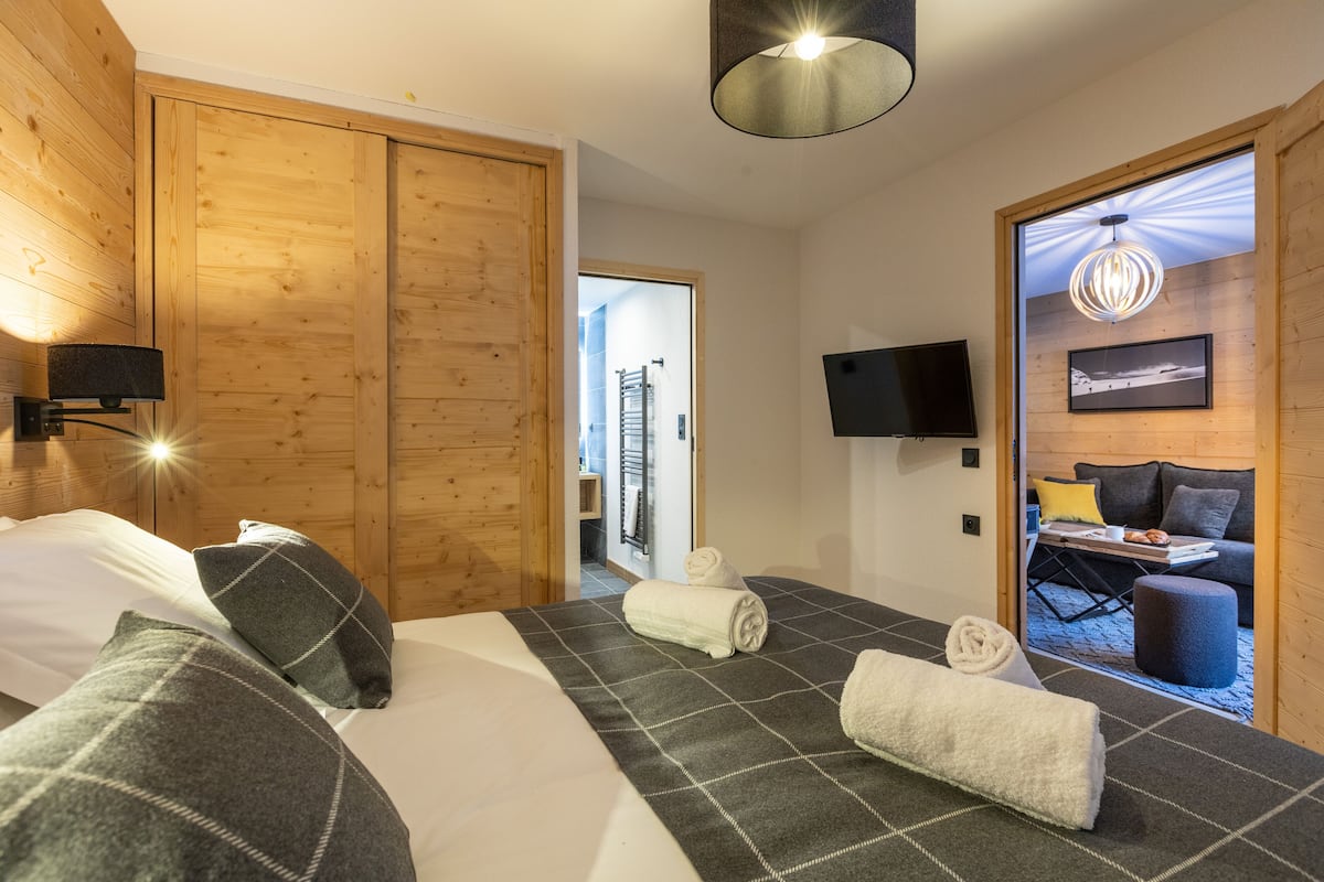 Ein Hotelzimmer mit Bett, Fernseher, Holzschrank und Blick nach draußen.