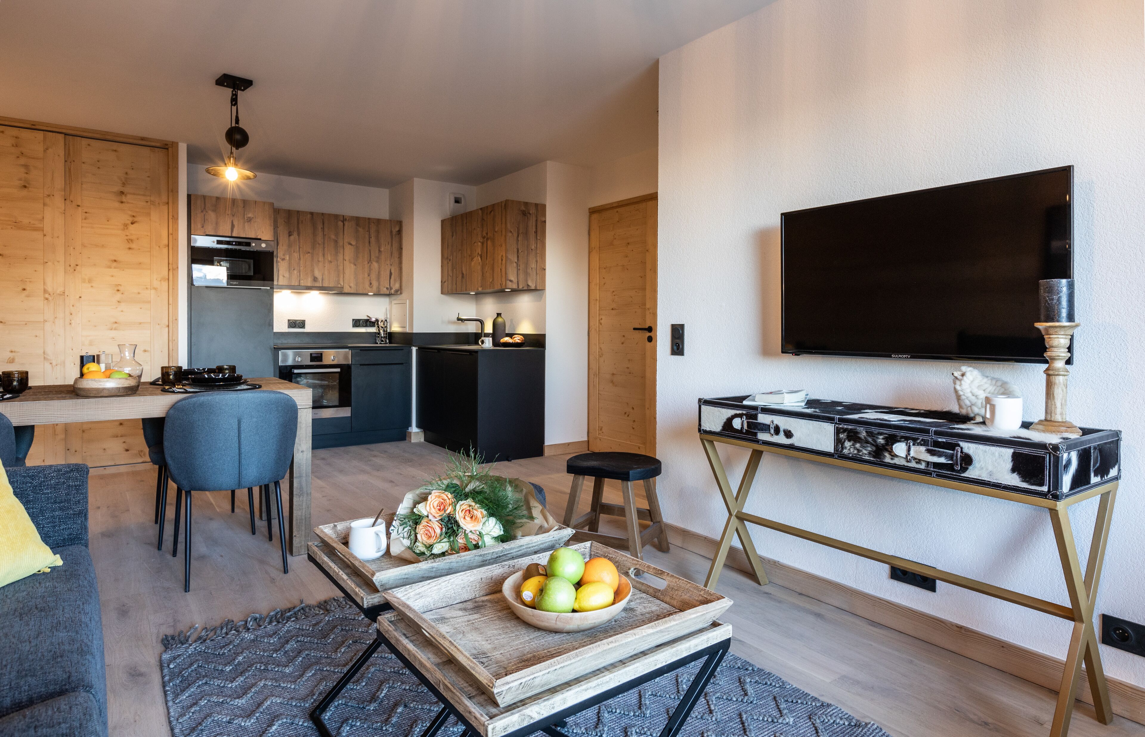 Een moderne keuken met houten kasten, een eethoek met tafel en stoelen, en een woonkamer met een bank en salontafel.
