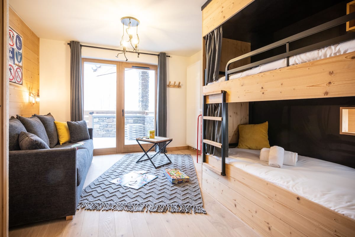 Ein gemütliches Zimmer mit Etagenbett, einer Schlafcouch, einem kleinen Tisch und einem Teppich.
