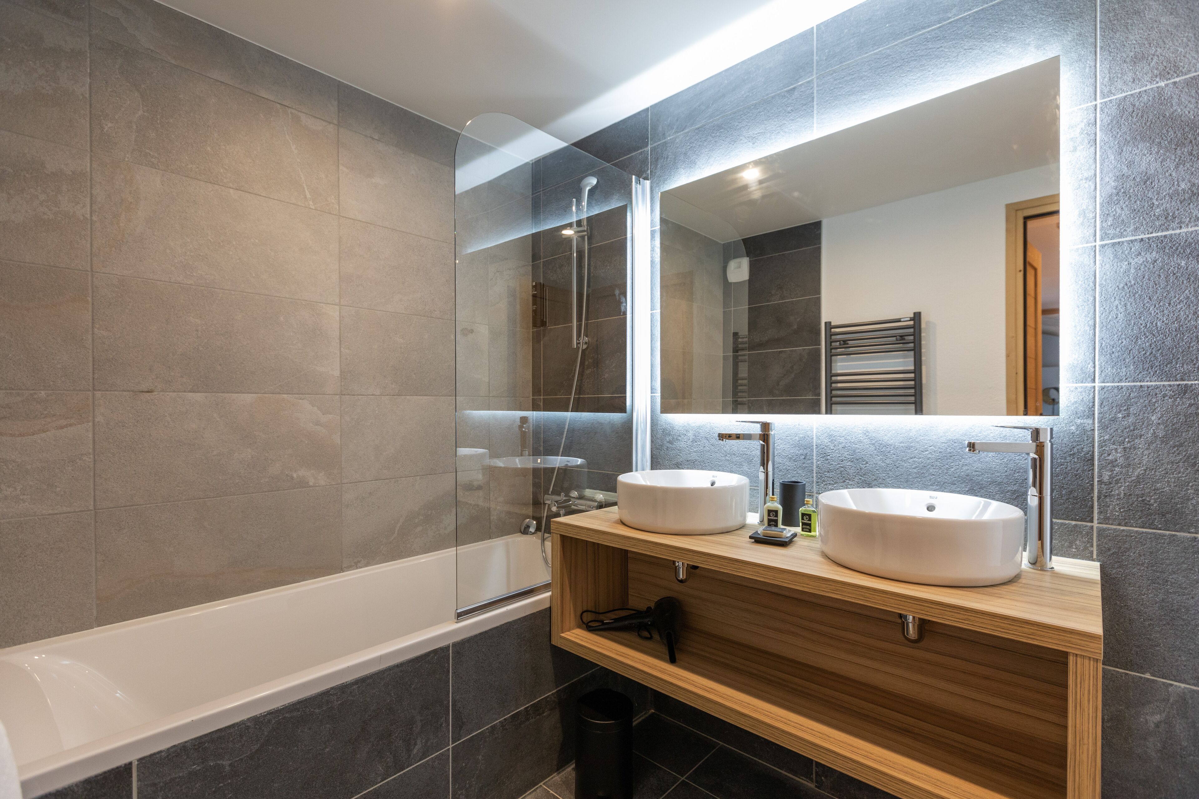 Ein modernes Badezimmer mit Badewanne, zwei Waschbecken und einem großen Spiegel.