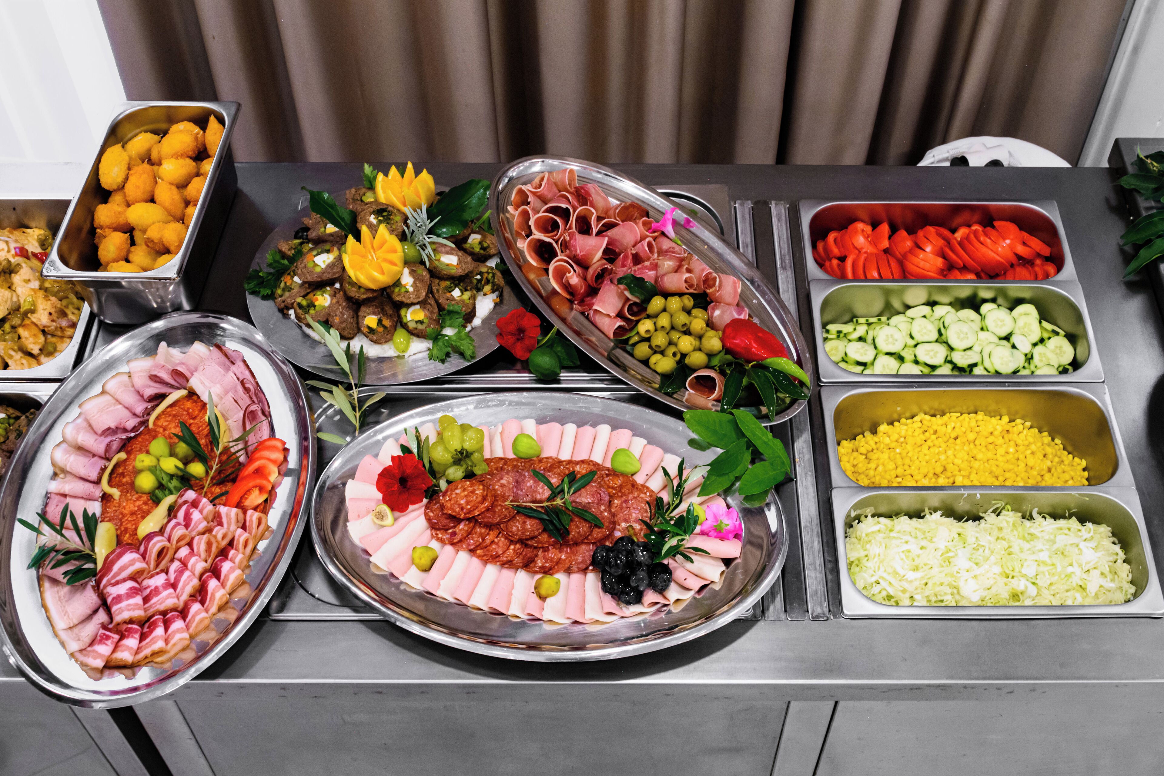 A buffet table with various food items including meats, vegetables, and fruits.