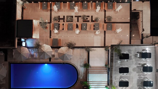 Vestíbulo de hotel con piscina, asientos al aire libre y una escalera.